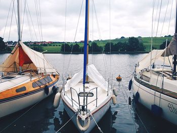 Boats sailing in river against cloudy sky