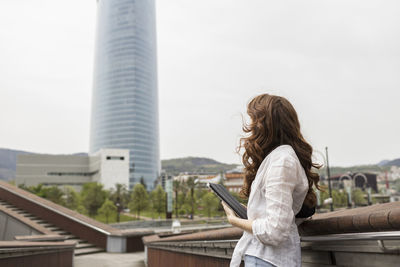Woman standing with digital tablet in city