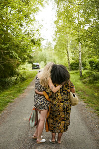 Two young women embracing on road