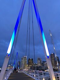 Suspension bridge in city against blue sky