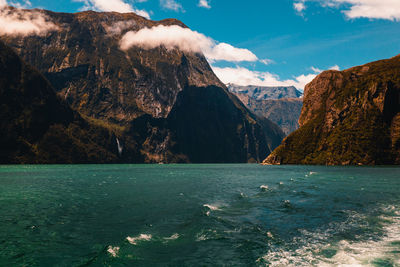 Scenic view of sea by mountains against sky