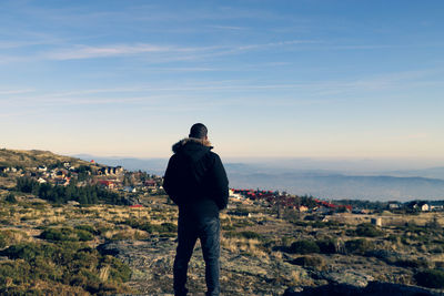 Rear view of man looking at cityscape against sky