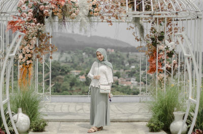 Portrait of young woman standing against building