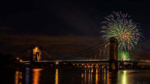 Illuminated bridge over river at night