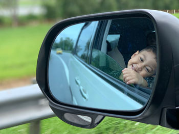 Reflection of boy in side-view mirror