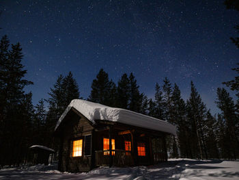 House by trees against sky at night