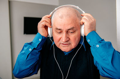 Senior man wearing headphones at home