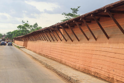 Empty footpath by road against sky