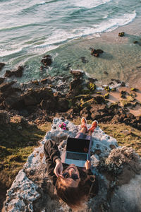 High angle view of woman sitting on rock at beach