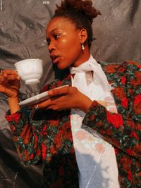 Woman holding coffee cup against fabric