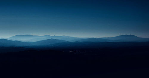 Scenic view of silhouette mountains against clear blue sky