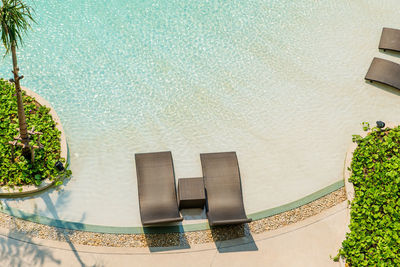 Beach chairs in luxury swimming pool at tropical hotel resort, relaxing and leisure time.