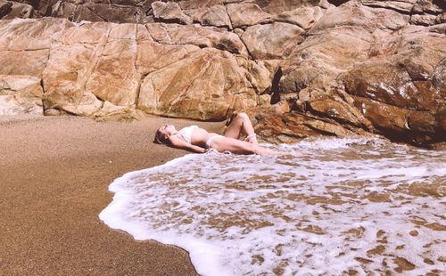 Full length of man relaxing on rock at beach