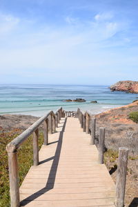 Wooden posts in sea against sky