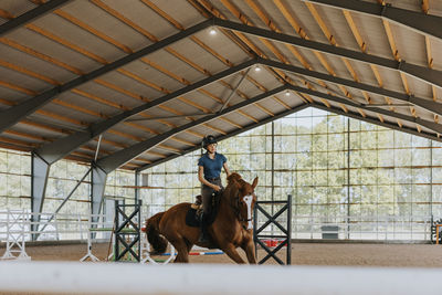 View of female horse rider using indoor riding paddock