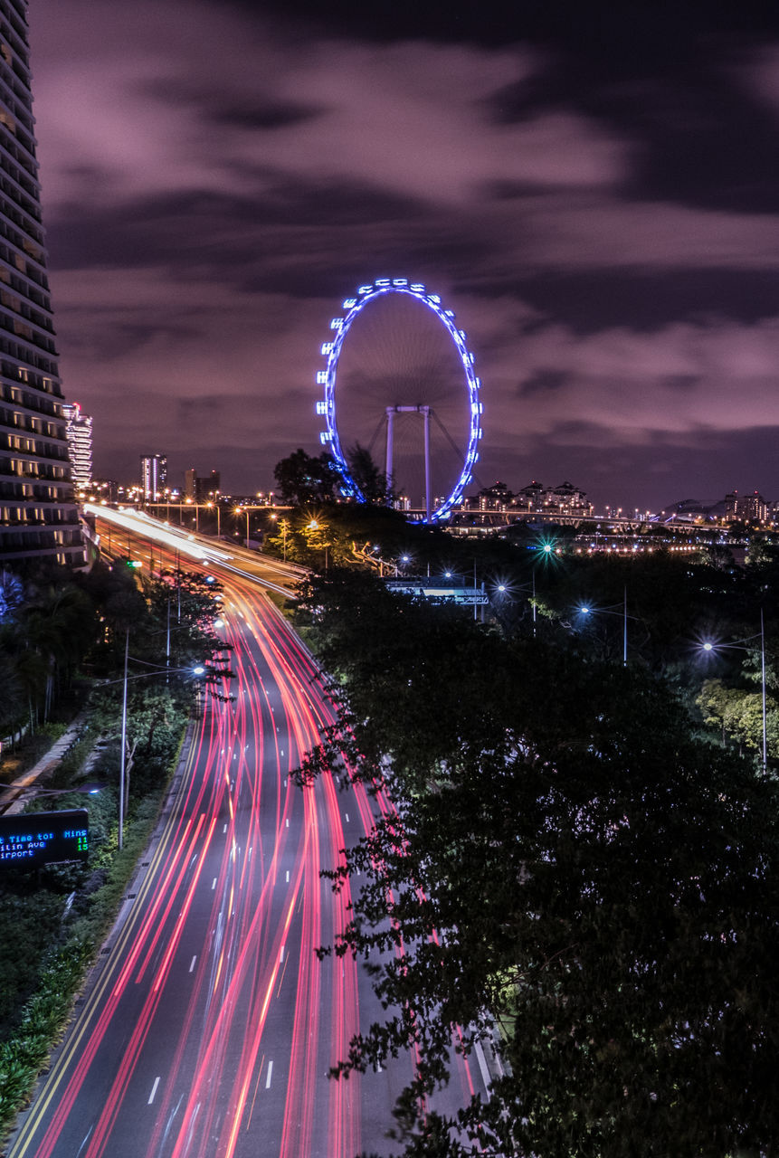 motion, night, illuminated, speed, long exposure, light trail, blurred motion, sky, outdoors, arts culture and entertainment, building exterior, no people, architecture, city, ferris wheel, cityscape, high street, tree