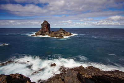 Scenic view of rocks in sea against sky