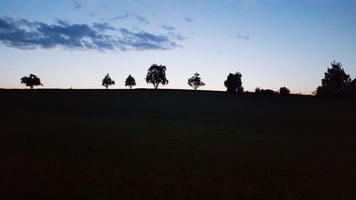 Silhouette trees on field against sky