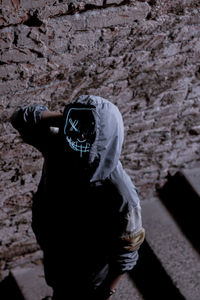 Rear view of woman standing against wall