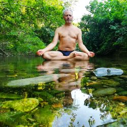 Full length of shirtless man in lake against trees