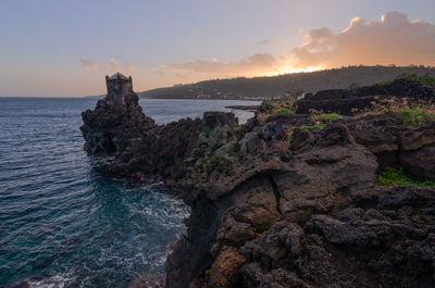 Rock formation on beach against sky during sunset