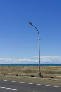 Street light on road against blue sky