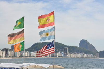 Multi colored flags against sky with mountain in background