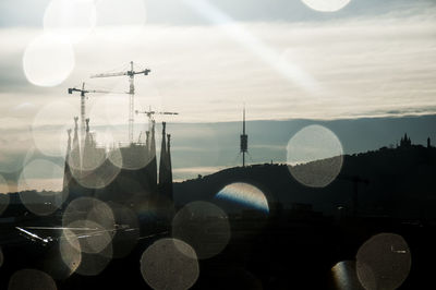 Close-up of communications tower against sky seen through glass window