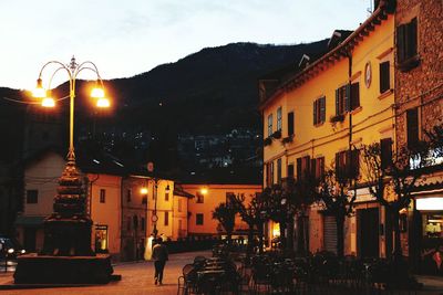 Illuminated street amidst buildings in city at night