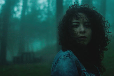 Young woman looking away against trees