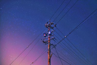 Low angle view of electricity pylon against blue sky