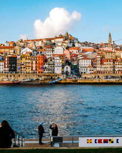 People by douro river against buildings in porto, portugal 