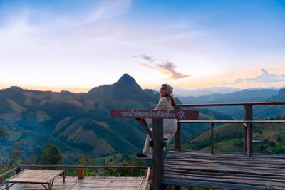 Rear view of man standing on mountain against sky