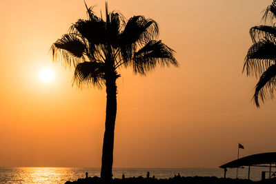 Silhouette tree by sea against sky during sunset