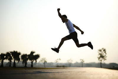 Low angle view of man jumping against sky