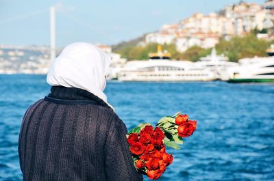 Close-up of woman with red roses against sea