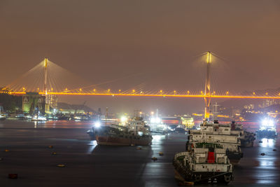Illuminated commercial dock by sea against sky at night