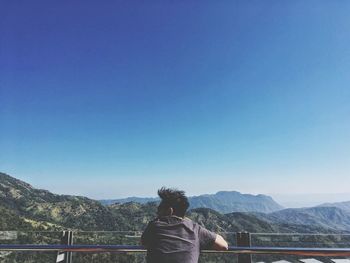 Man standing on mountain against clear blue sky