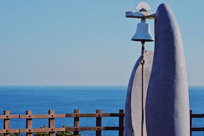 Bell hanging at beach against clear sky