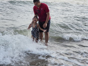 Man and son standing on shore at beach