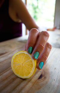 Cropped hand of woman holding lemon at table