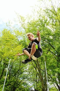 Boy with cross-legged levitating against trees