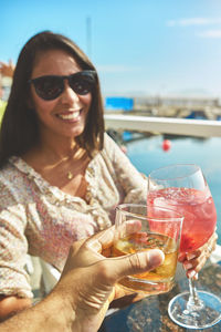 Couple toasting the beginning of summer at marina, cheers cups and glass, summer concept.