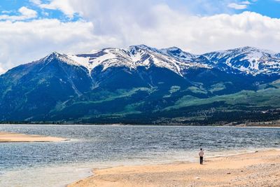 Man standing on snowcapped mountains by sea against sky