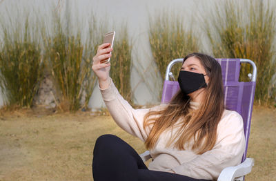 Young woman using mobile phone while sitting outdoors