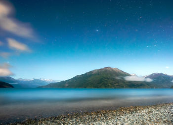 Scenic view of lake and mountains against blue sky