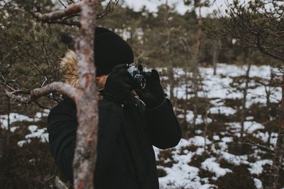 Reflection of man photographing on snow covered field