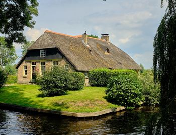 House by lake against sky