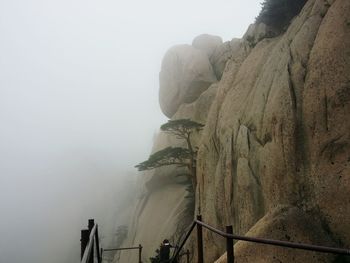 Low angle view of people on cliff in foggy weather