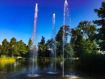 Low angle view of water fountain against clear blue sky